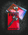 Pin with ax design on a red background, featuring 'NICKFILTH.COM' text, on a dark textured surface.