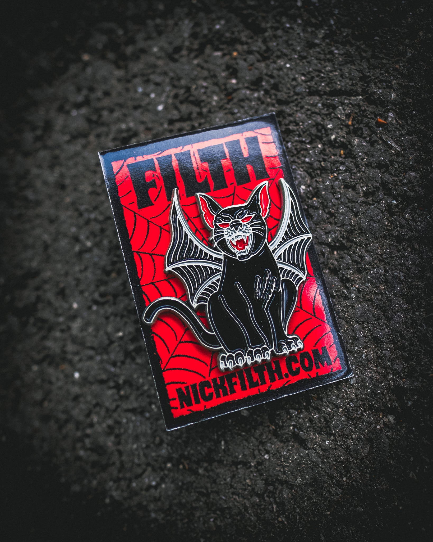 Enamel pin with a black cat design on a red background, featuring the brand 'NICKFLITH'.