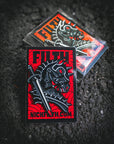 Two black and red pins with a Horse and sword design on a dark textured background.